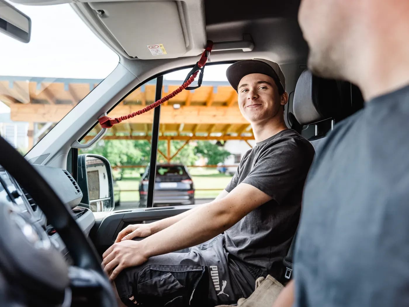Junger Mitarbeiter am Steuer des Firmenfahrzeugs von Elektrotechnik Biller